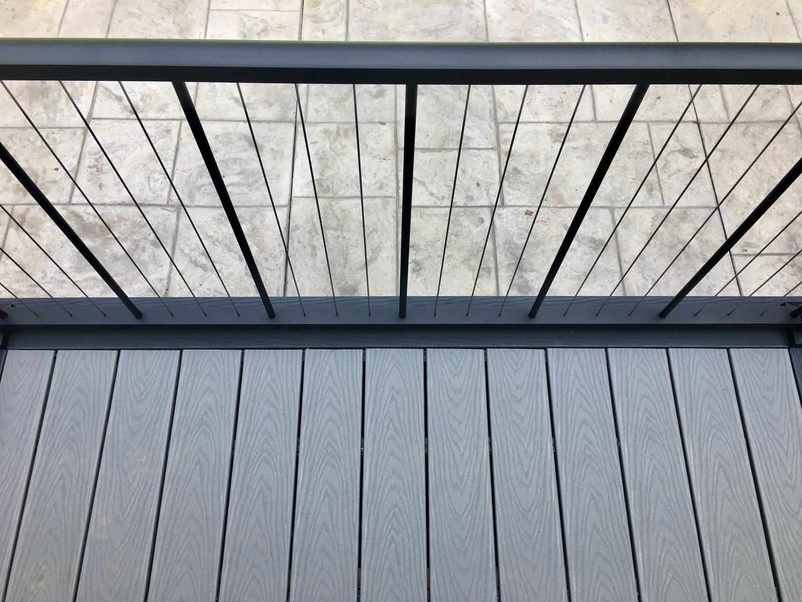 Close view of gray composite boards, dark border and black aluminum balusters
