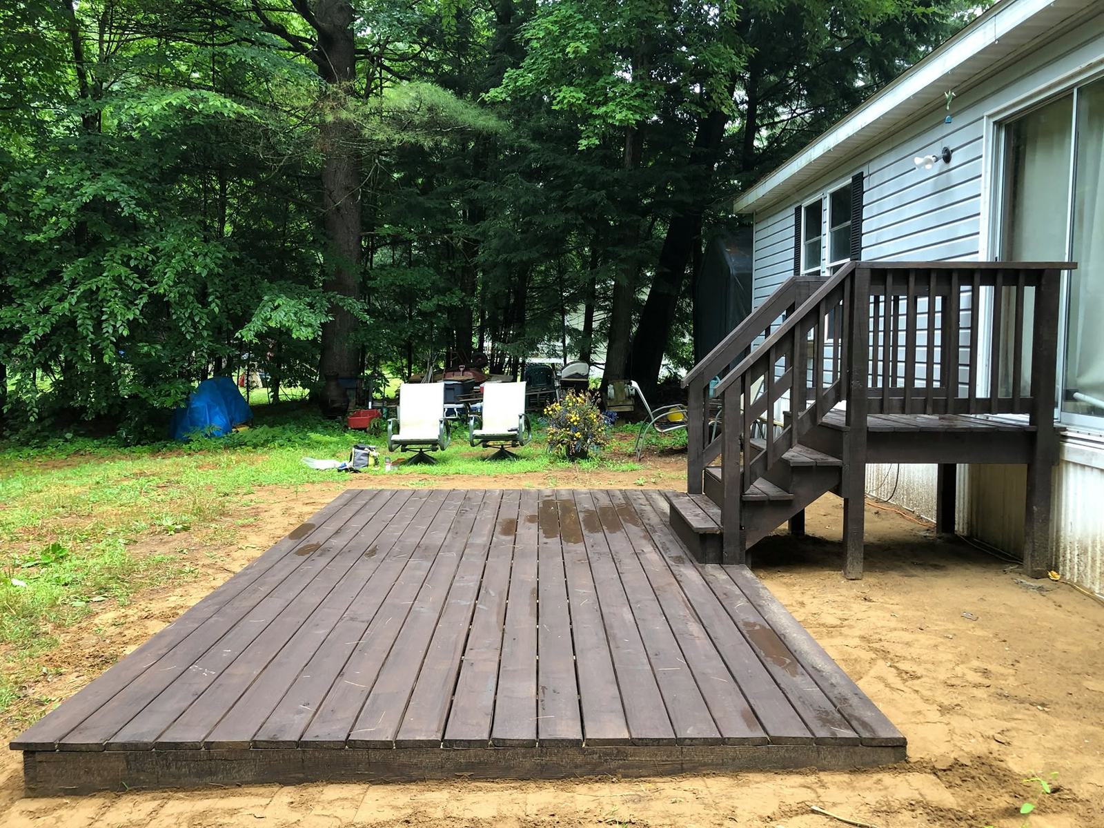Dark-stained platform deck and steps in a wooded yard