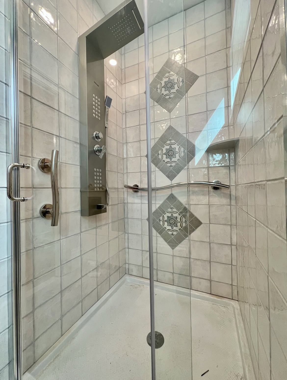 Tiled walk-in shower with diamond accent tiles and a shower panel