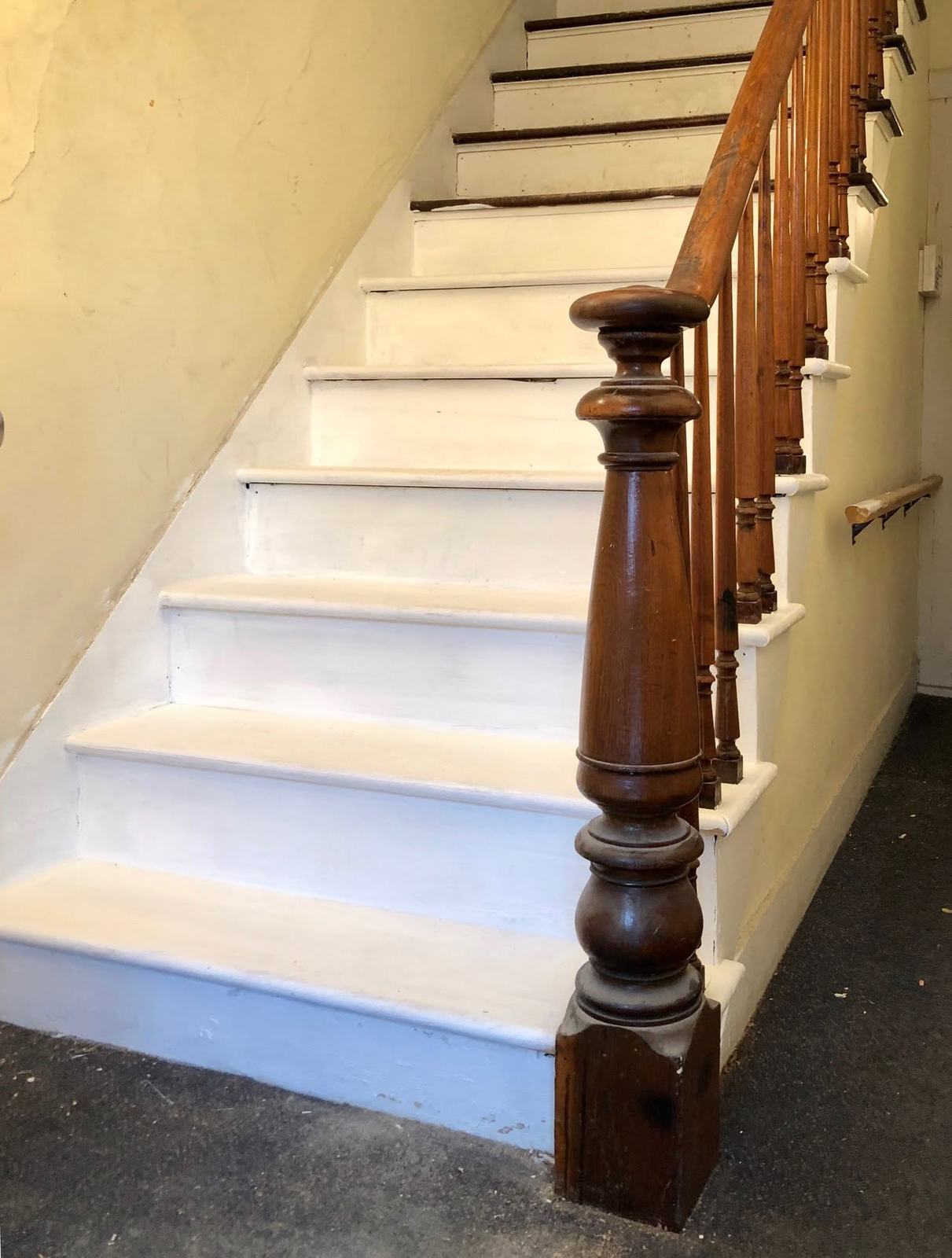 Staircase with white risers and a dark turned newel post